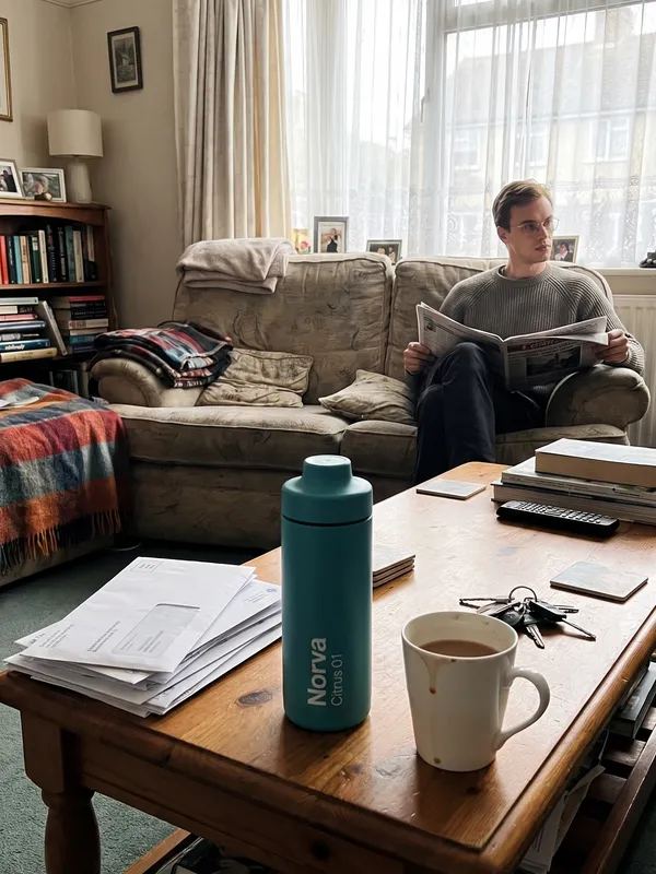AI generated product photo of a teal canister bottle on a cluttered living room coffee table, shot like a casual phone photo
