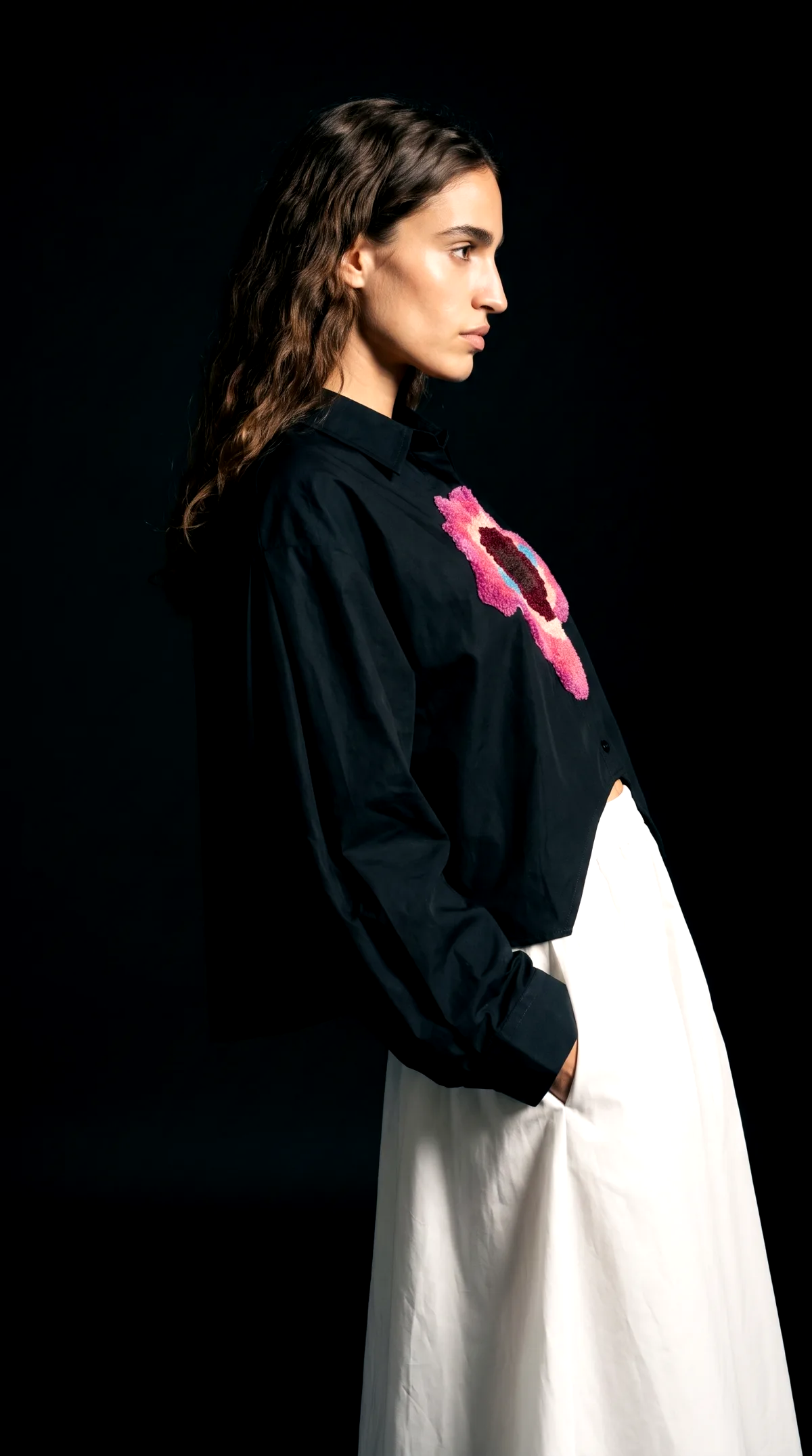 AI generated studio photoshoot of a black embroidered shirt, profile view on a dark backdrop