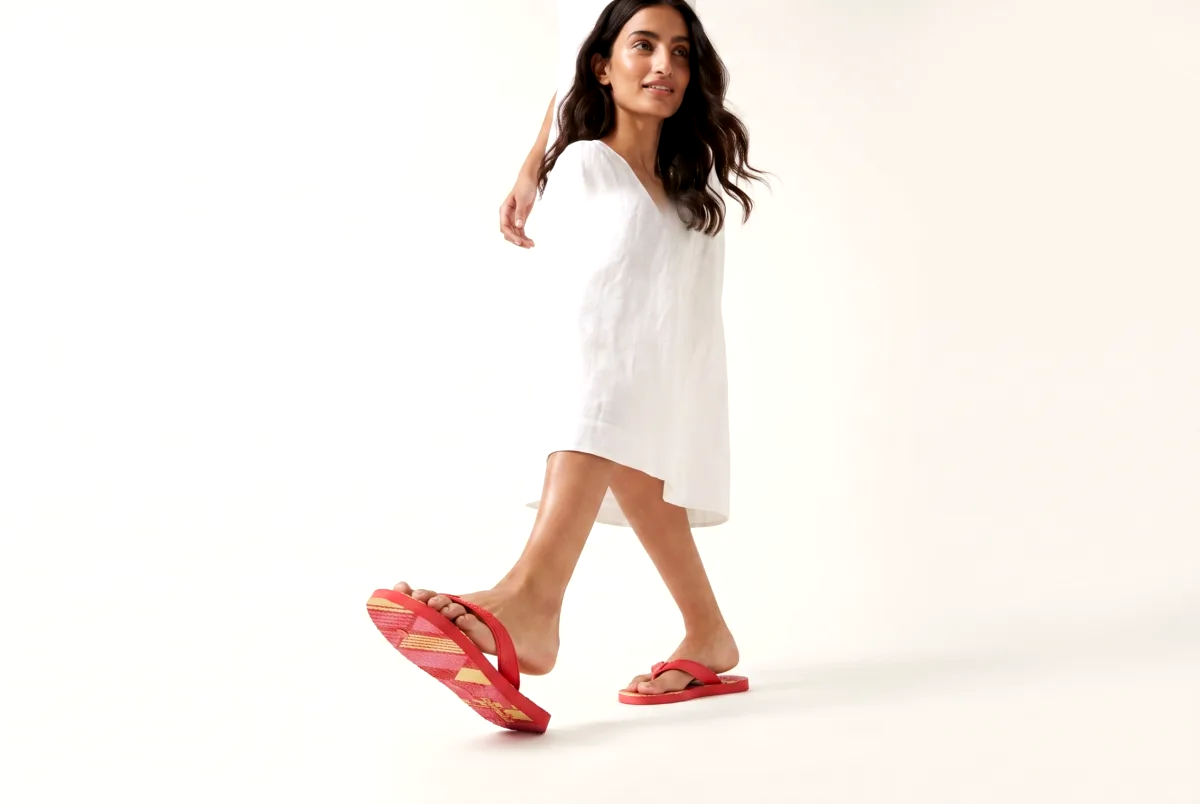 AI generated product photo of a linen dress and flip flops in a warm off-white studio scene